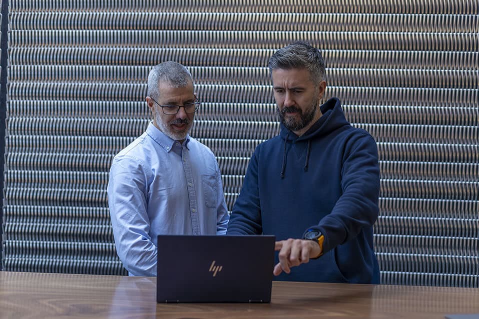 Two TectoniQ team members reviewing the TIQ platform on a laptop
